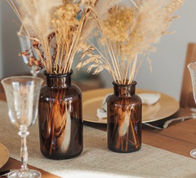 braune Apothekerflaschen mit Trockenblumen als Tischdekoration